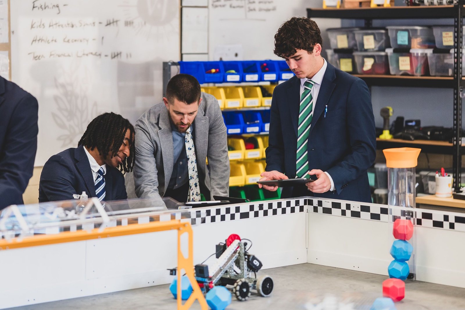 Students and a teacher gathered around a robotics build on a workbench