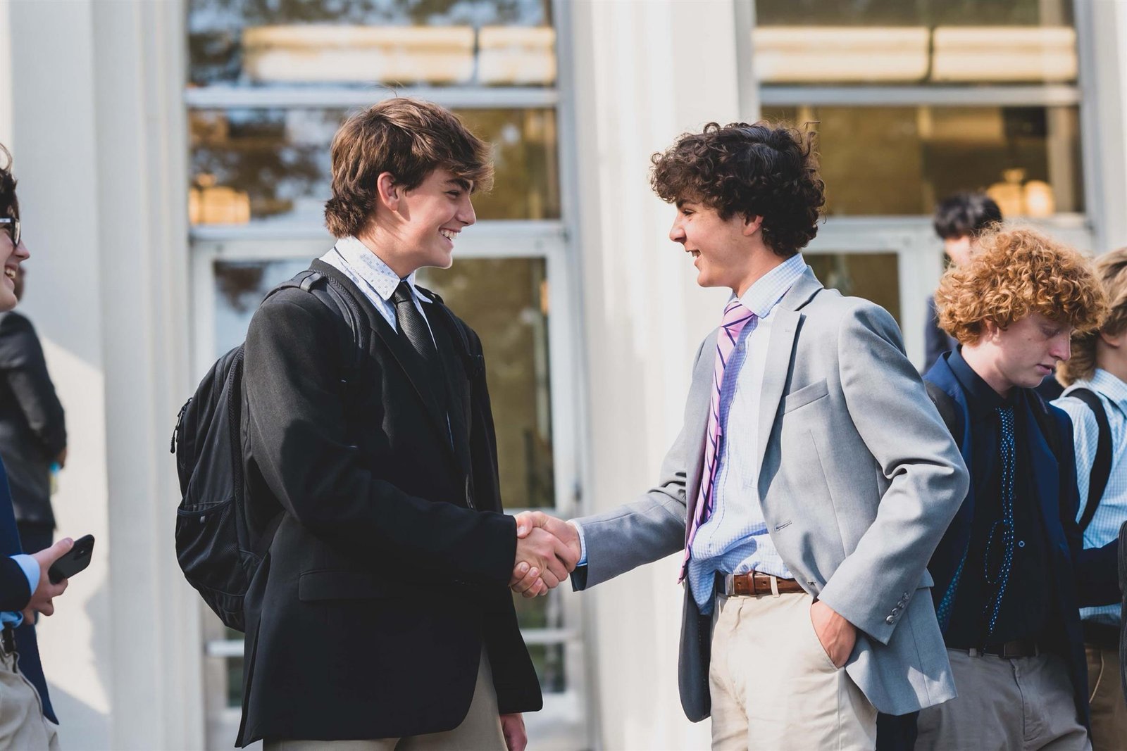 Two Salesianum students shaking hands on the front steps between classes