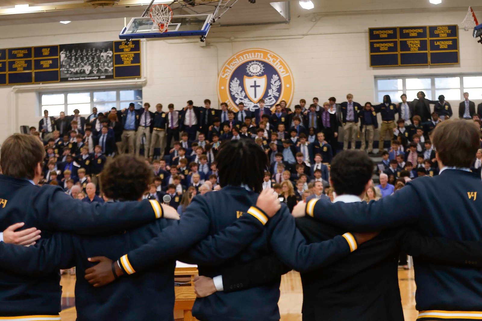 Salesianum students linking arms in the gym before a school assembly